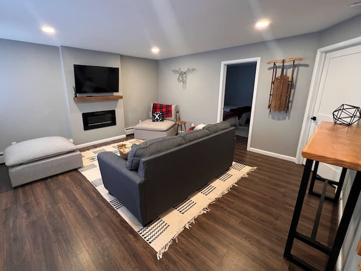 Lower level living area with 50" Amazon TV, electric fireplace, and sleeper sofa.
