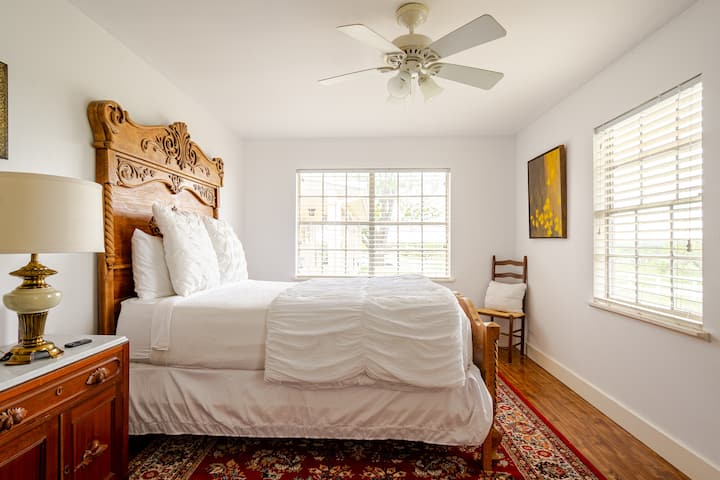 The second master bedroom showcases a beautiful queen-size antique bed with a wooden frame, an oriental rug, an attached full bathroom, and some of the best views on the property!