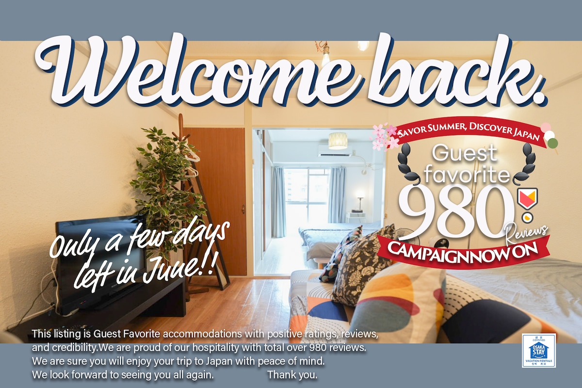 A welcoming sign greets guests with information about current promotions. The background reveals a glimpse of the apartment's entryway, featuring clean lines and a bright interior, suggesting a comfortable and inviting space. Natural light filters through the open doorway into the living area.