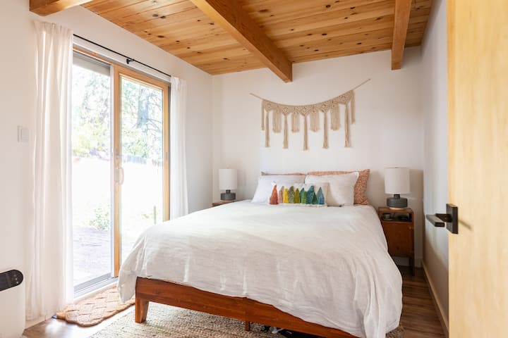 cama tamaño queen con cómodas sábanas de algodón durante los meses cálidos y lindas sábanas de franela de algodón suave durante los meses fríos 
salir por la puerta corrediza de cristal al patio trasero con comedor al aire libre y Softub bajo árboles de hoja perenne altos