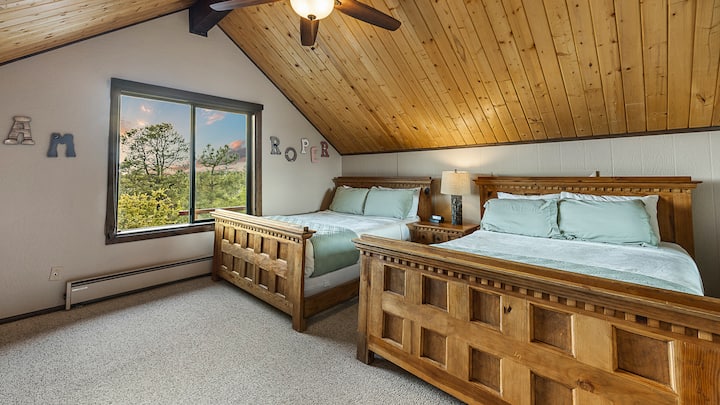 מיטות זוגיות, גווני עץ חמים וחלון עם נוף יוצרים מקום מסתור נעים.