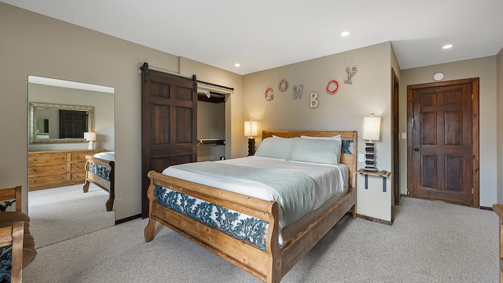 חדר שינה קווין סייז כפרי עם מיטת עץ, דלת אסם ושלט "בוקרי" שובב. עם גישה לחדר רחצה צמוד.