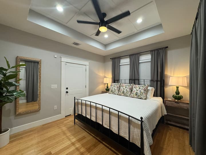 Primary bedroom with queen bed, own TV, his and hers nightstands with wireless phone charging reading lamps. Beautiful room details like high ceiling and plenty of windows.