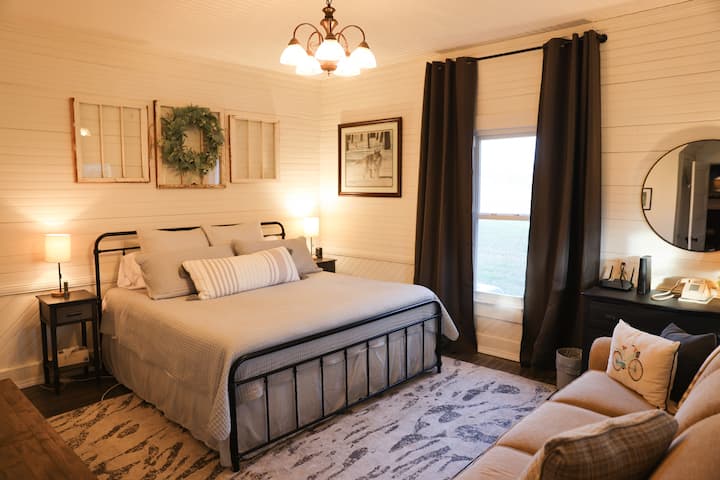 King sized bed and couch in Bedroom 1. Stairs to upstairs are located in this room.