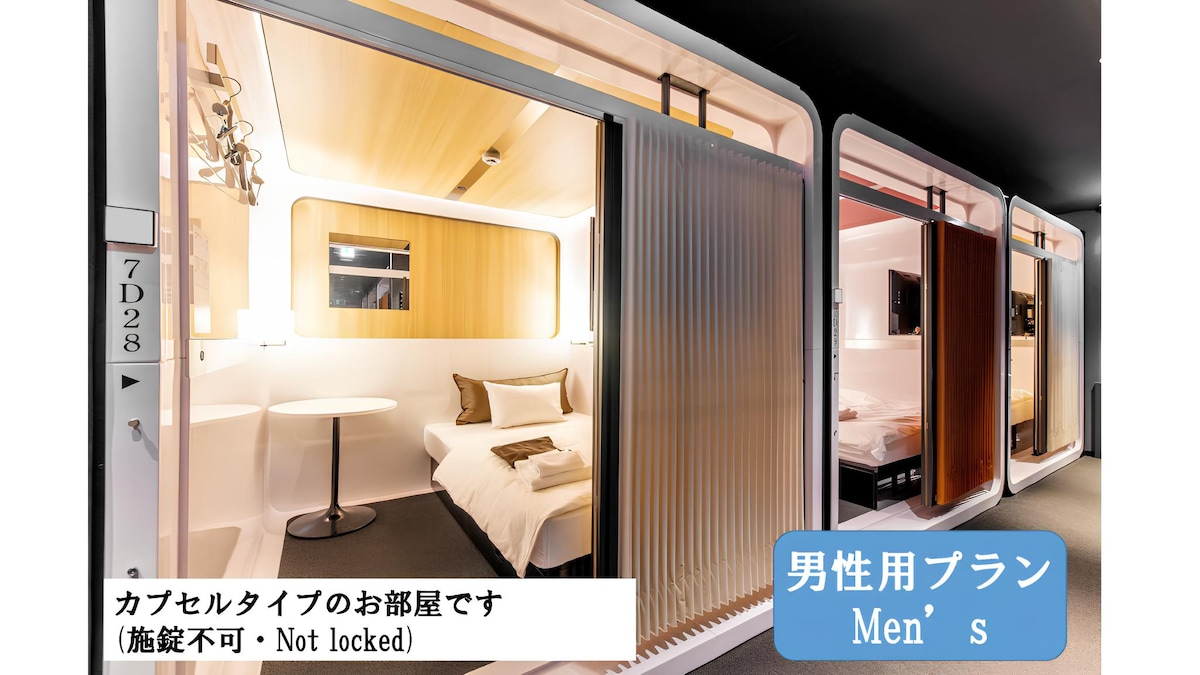 A capsule-style room is featured, showcasing minimalist design with soft lighting. Each capsule is equipped with a spacious bed and a small shelf for personal items. The open layout provides communal access, enhancing the overall guest experience.