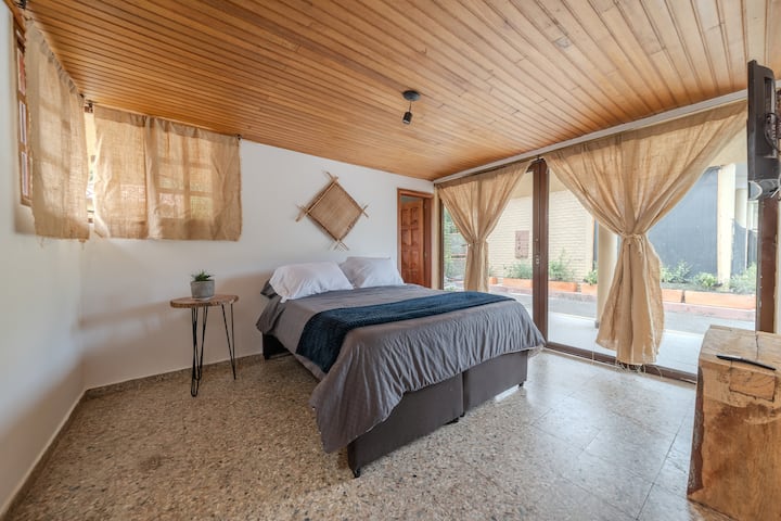 Cama doble y nido con colchón premium. Baño privado, luz natural y puerta ventana al exterior. El techo en madera mantiene la alcoba caliente. Un refugio íntimo para descansar viendo el cielo y respirando naturaleza.