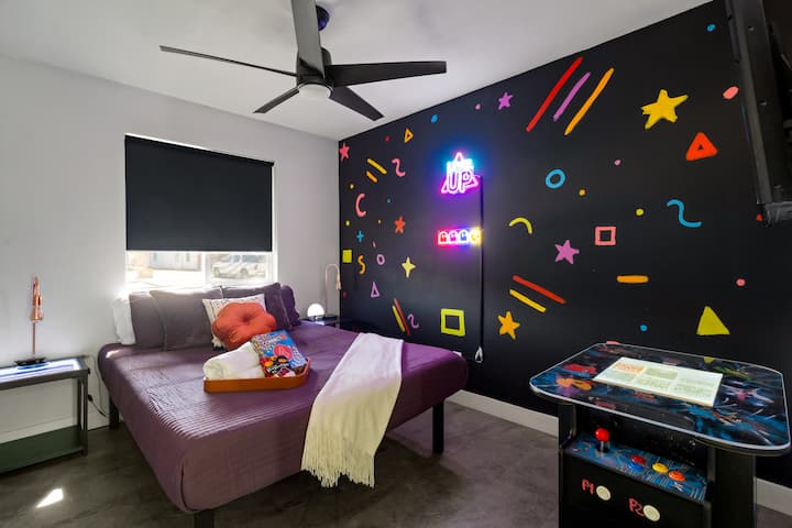 Chambre lumineuse de style rétro avec un néon coloré, un décor ludique et beaucoup d'espace.