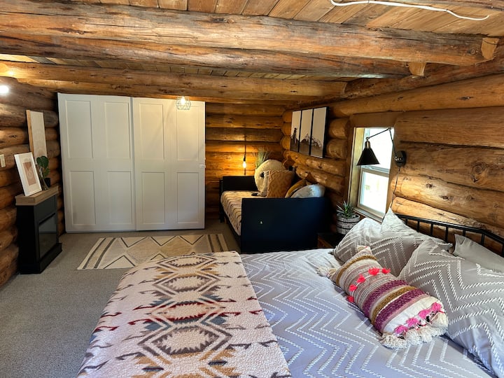 Slaapkamer op de begane grond met kingsize bed en twee eenpersoonsbedden met open haard en tv 