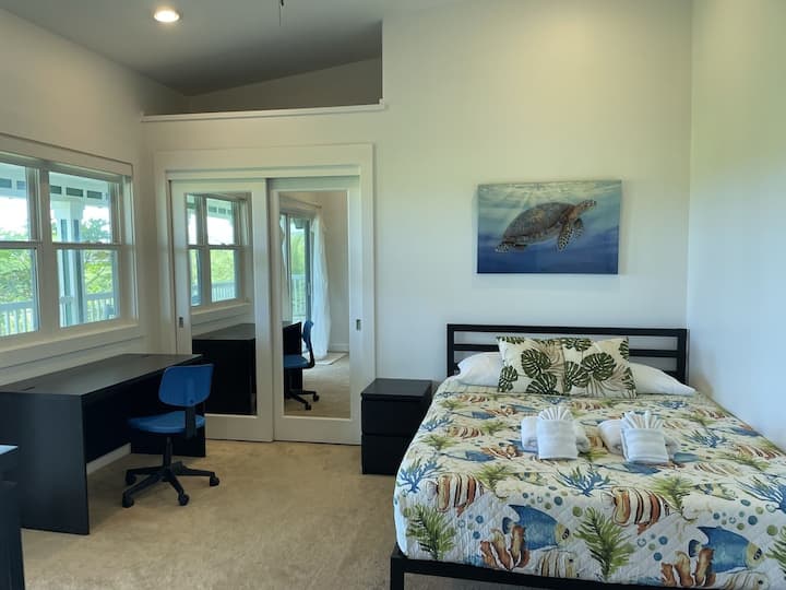 חדר שינה עם נוף לאוקיינוס ופינת עבודה ייעודית.