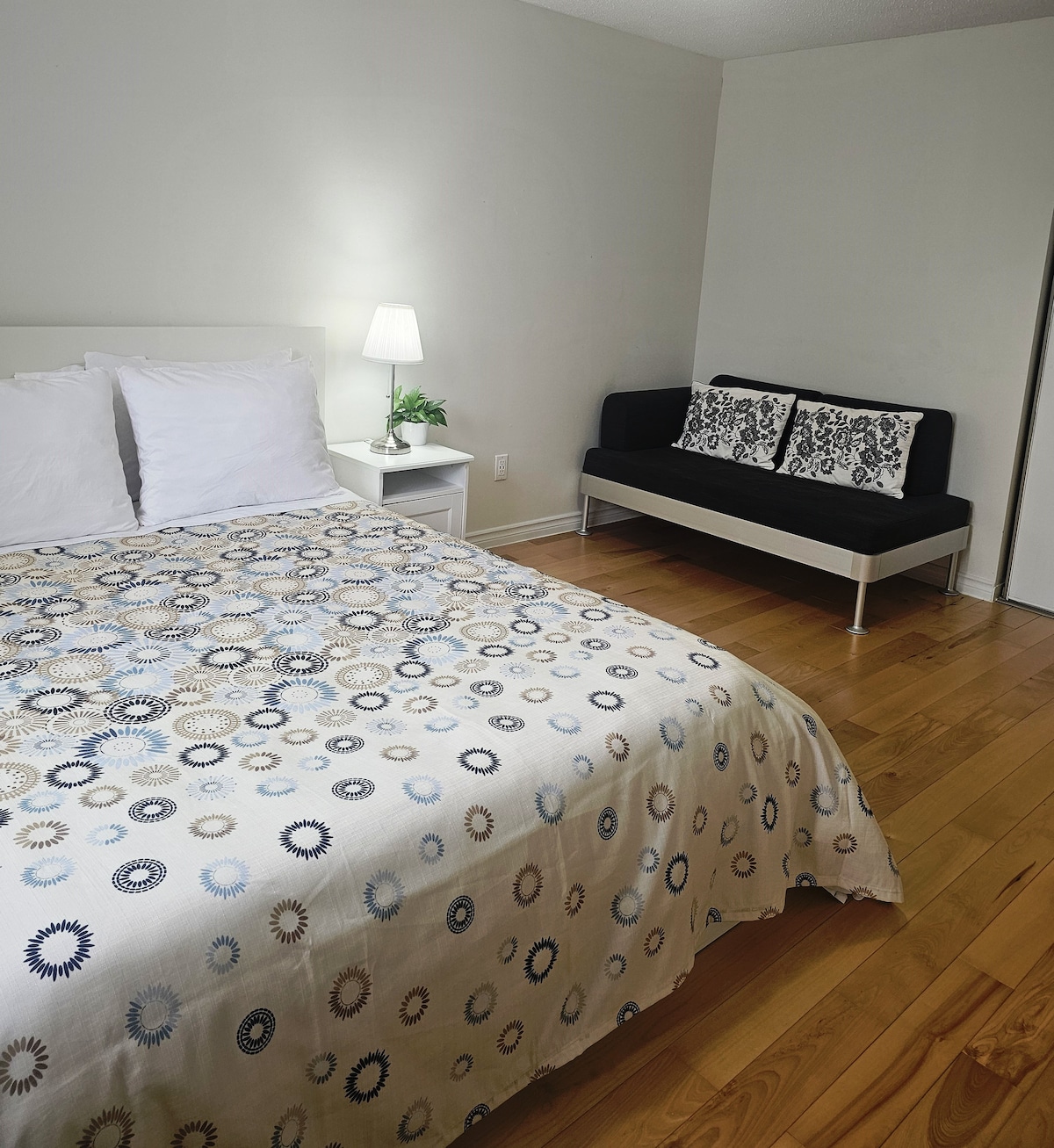 卧室配备标准双人床，设施齐全。现代墙漆，配备2张床头柜和灯具。硬木地板，配有大窗户，日光充足。1双人沙发座椅布置、衣橱、时钟、垃圾桶和装饰植物为这间卧室增添了时尚外观