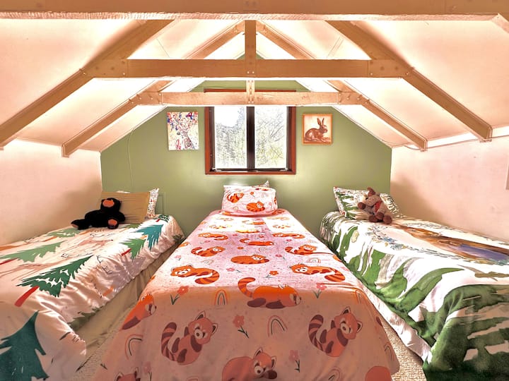 Este es el tercero de 3 dormitorios en la casa principal. Hay una escalera de caracol que conduce a un loft que tiene tres camas individuales, juguetes, juegos, un ventilador y una silla.