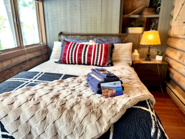 Experience comfort in this bedroom, situated at the far side of the cabin. With its plush queen mattress, you'll feel pampered and relaxed. Plus, you can savor breathtaking views of the serene lake and lush woods right outside your window. 