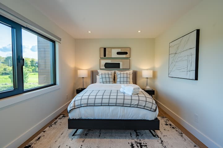 Просторна спалня за гости на втория етаж с двойно легло, самостоятелна баня, дрешник, с прозорци на юг, с дистанционно управление на щорите за поверителност и 40-инчов смарт телевизор за забавление.