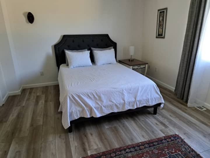 The bedroom includes a comfortable queen bed and blackout curtains for a tranquil night's rest.