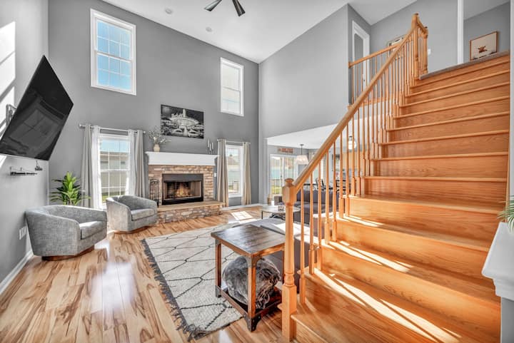 Pumzika na burudani katika sebule yenye nafasi kubwa yenye televisheni ya '65', meko, kochi kubwa la sehemu, viti 2 vya kuteleza, mwonekano wa ua wa nyuma na jiko lililounganishwa kwa ajili ya sehemu ya wazi!