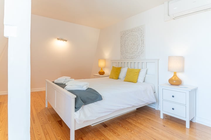 Perspektiva e dhomës së gjumit 2, që ndodhet në katin e poshtëm të apartamentit; mund të dallojmë krevatin dopio, ajrin e kondicionuar dhe një tra druri, origjinale të kësaj ndërtese të shekullit të nëntëmbëdhjetë.