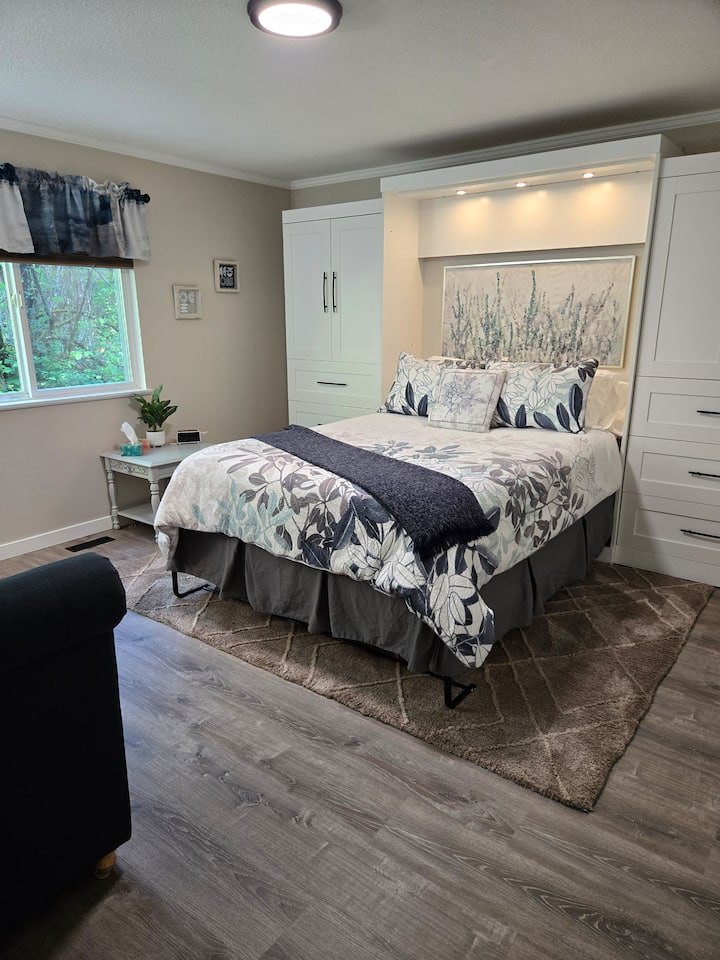 ห้องนอนควีนไซส์มีพื้นที่ตู้เยอะ โคมไฟอ่านหนังสือเหนือศีรษะพร้อมสวิตช์ข้างเตียง หน้าต่างมองออกไปยังพื้นที่อนุรักษ์ที่อยู่ติดกัน