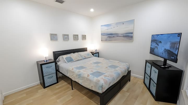 Cozy retreat decor with queen bed, TV, spacious closet, adjacent bathroom, USB reading lamps, and 110V outlets on both sides for easy device charging.