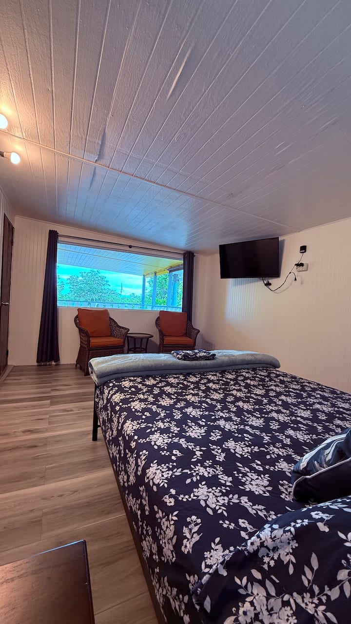 Relax and unwind lookin the bay fron our glass wall in this inviting second-floor bedroom at Cabañas Muelle, featuring a comfortable queen bed, smart TV, and refreshing air conditioning. Enjoy the cozy seating area and views from your private retreat