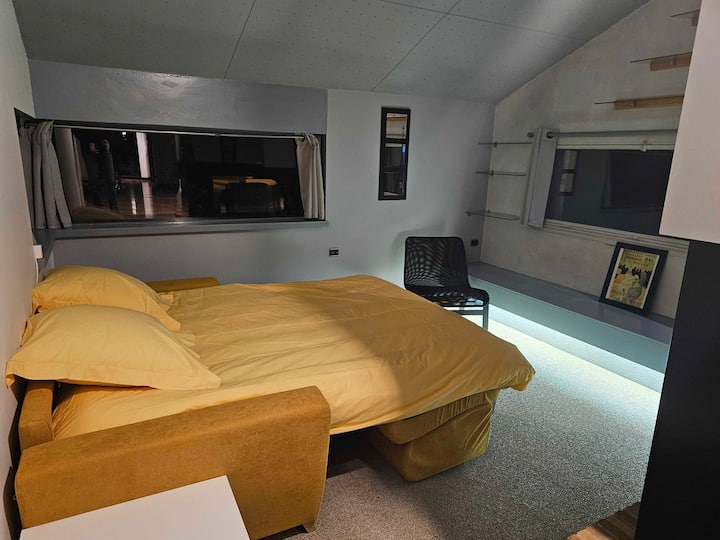 Sofá cama con una parte de un biombo que permite un mínimo de privacidad con la sala de estar cercana.