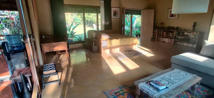 Kuanzia kushoto kwenda kulia: mtaro wa Villa Limasan, kona ya kufanya kazi ndani ya sebule kuu, kitanda cha ukubwa wa malkia, rafu za vitabu, sofa yenye starehe. Mwangaza wa asubuhi.