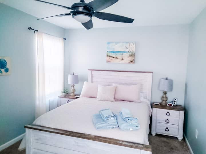 Relájate en este dormitorio principal del segundo piso, con una acogedora cama tamaño queen, tonos playeros suaves y luz natural suave. Perfecto para relajarse después de un día bajo el sol, con lujosas sábanas y un ambiente tranquilo para combinar con la orilla a pocos minutos.