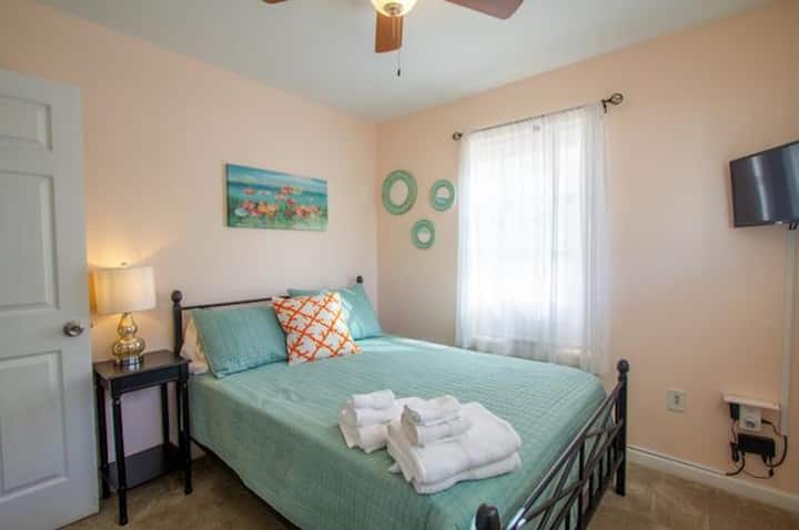 Este alegre dormitorio de la planta principal ofrece una cama de matrimonio, suaves detalles costeros y un ambiente tranquilo que es perfecto para mañanas perezosas o siestas después de la playa. Este dormitorio también tiene un televisor, un gran lugar para relajarse después de un día de sol y arena.