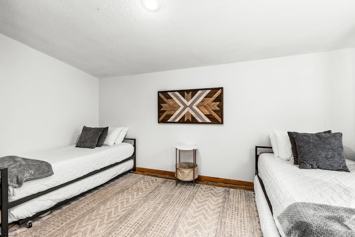 This cozy bedroom offers two twin beds, making it the perfect space for kids or guests to enjoy a restful night. A large piece of eye-catching artwork adds a vibrant touch, creating a stylish and inviting atmosphere. 