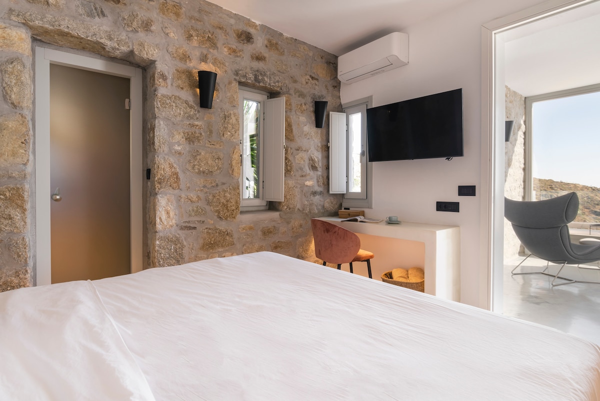 Upplev mykonisk lyx med ett påkostat sovrum och eget badrum, prydd med utsökt design. Fördjupa dig i avkoppling, njut av lugna stunder med stil