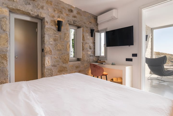 Përjeto luksin mikonian me një dhomë gjumi luksoze dhe banjë ngjitur, të zbukuruar me dizajne të shkëlqyera. Zhytu në çlodhje, duke shijuar momente të qeta në stil