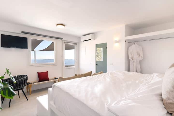 Përjeto luksin e frymëzuar nga Mykonos: çlodhu në një dhomë gjumi luksoze me një banjë ngjitur, të zbukuruar me dizajn të shkëlqyer mikonian, i përsosur për momente çlodhjeje të qetë