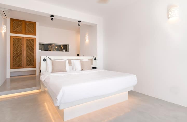 Përjeto çlodhjen më të mirë në një dhomë gjumi luksoze me banjë ngjitur, të frymëzuar nga dizajni mikonian, i përsosur për momente të qeta.