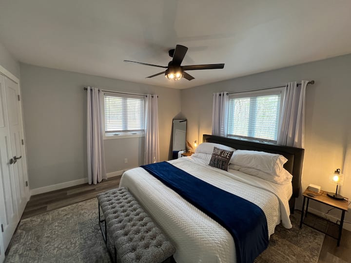 Chumba cha kulala #2 kwenye ghorofa kuu na kitanda cha ukubwa wa kifalme, feni ya dari, roshani, rafu ya mizigo, kioo cha urefu kamili, mapazia ya giza ya chumba, taa zilizo na bandari za USB, makabati 2.