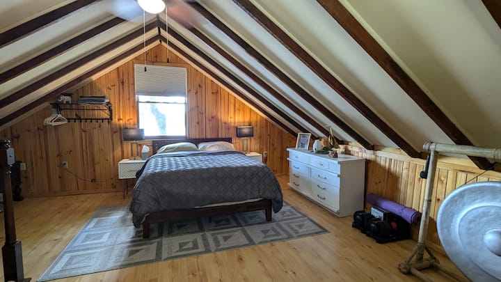 Amplio dormitorio principal arriba. Hay unas vistas espectaculares del lago por la ventana. ¡La esterilla de yoga, las mancuernas de peso ajustable y las bandas de ejercicio elásticas están a la derecha, junto con un gong solo por diversión! Oficina y medio baño al otro lado de la habitación.