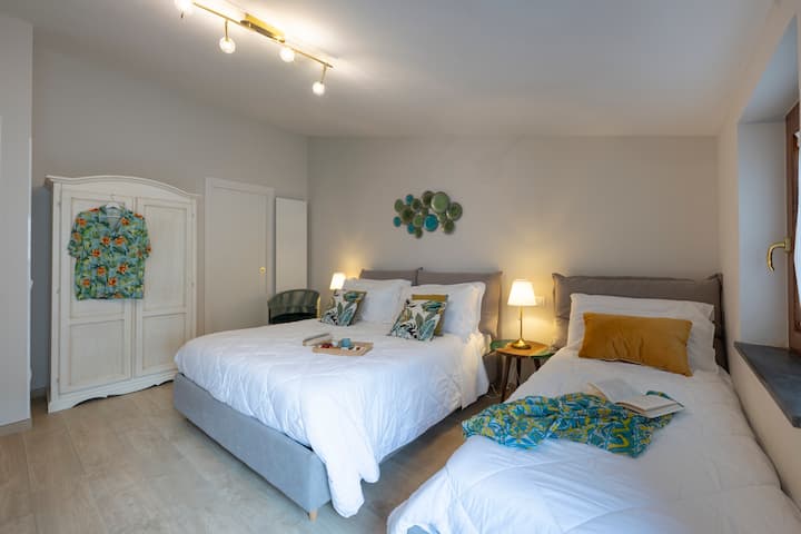 Dormitorio principal con cama matrimonial y cama individual, esquina de trabajo, TV con acceso a Netflix. El baño privado completa la experiencia, mientras que la exclusiva terraza ofrece un rincón de tranquilidad al aire libre.