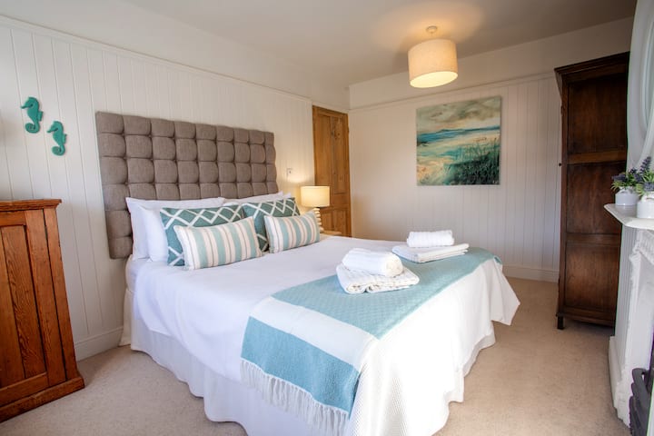 Kitanda cha ukubwa wa King katika chumba kikuu cha kulala, chenye nafasi ya kutosha kwa kitanda cha kusafiri katika chumba hiki