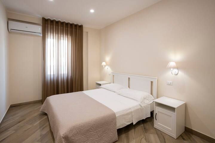 Muhtasari wa chumba ulio na kitanda cha watu wawili, taulo, meza za kulala 