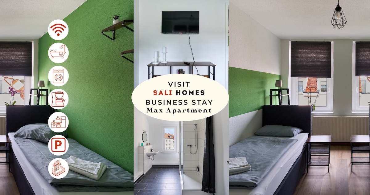 The sleeping area is highlighted by green accent walls and features two single beds with dark bedding. A wall-mounted TV is positioned in front, and windows allow natural light to flood the room. Shelving units provide additional storage and decor.