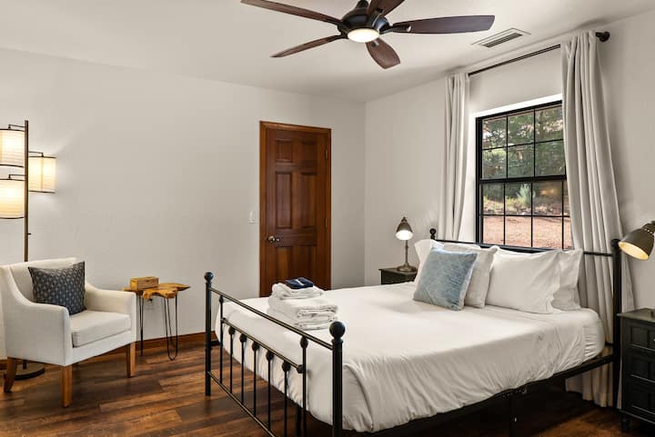Bedroom 3 features a plush queen bed dressed in crisp, hotel-quality linens that stand out against a warm wooden palette