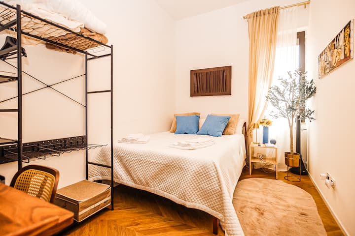 Soba „Lucca” s bračnim krevetom, odjećom + stalkom za prtljagu, radnim stolom i stropnim ventilatorom. Pogled na grad i Monte Cetonu. 