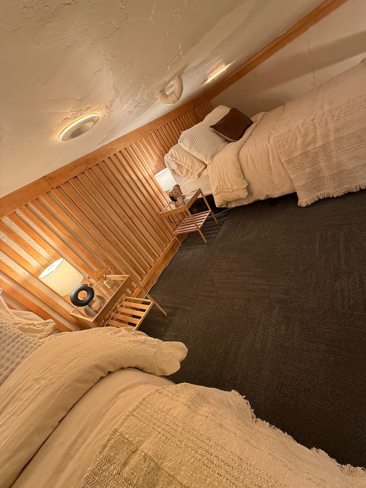 לופט שינה עם שתי מיטות בגודל מלא ותקרה נמוכה.