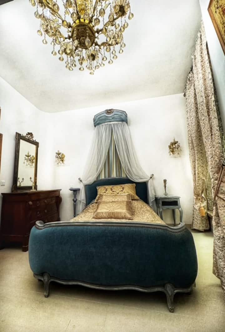 Tretia spálňa s manželskou posteľou zdobenou ručne vyrobeným baldachýnom a útulnou sediacou áriou so starožitnými gobelínmi.