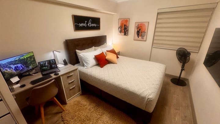 سرير بحجم كوين، مروحة أرضية، مكتب مع كرسي.