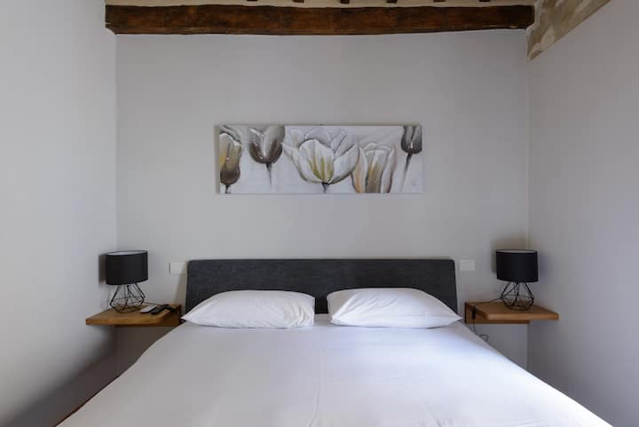 Área para dormir, dormitorio con cama TAMAÑO KING, TV inteligente y vestidor personal, con vistas al centro histórico y pequeñas tiendas.