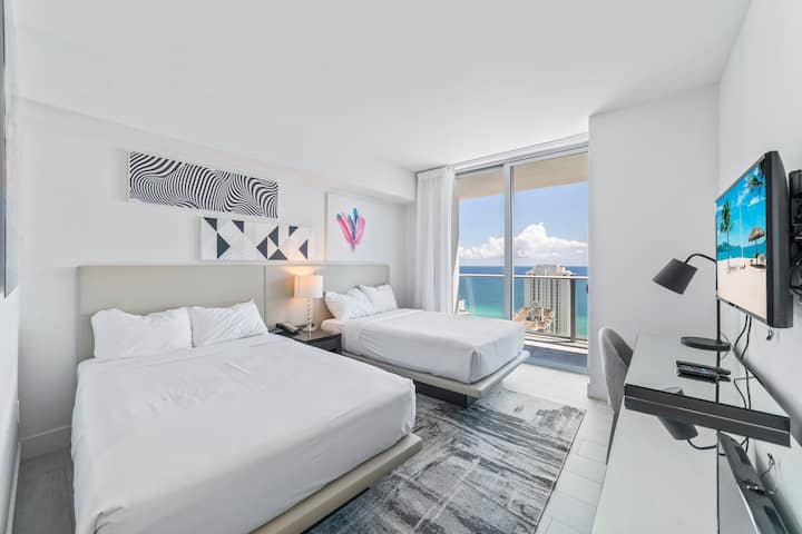 Შეაბიჯეთ მეორე საძინებელში, რომელშიც არის ორი ორადგილიანი საწოლი რბილი ნეიტრალური თეთრეულით, მყუდრო სამუშაო მაგიდით და თანამედროვე ხელოვნების ნიმუშებით. Იატაკიდან ჭერამდე ფანჯრებიდან აივნის ხედი იშლება, ხოლო ცალკე სააბაზანო უზრუნველყოფს კომფორტსა და კომფორტს.