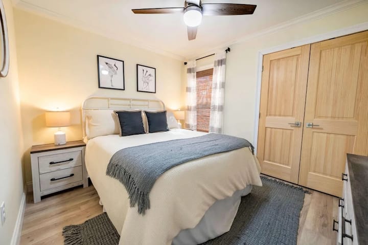 غرفة نوم في الطابق العلوي بسرير بحجم كوين مُجهزة بألوان ناعمة ومحايدة، وتلفزيون ذكي مُثبت على الحائط، وخزانة ملابس للتخزين الشخصي. تضيف مروحة السقف والإضاءة بجانب السرير الراحة والوظائف. بسيط، جذاب، وسهل الاستقرار فيه.

