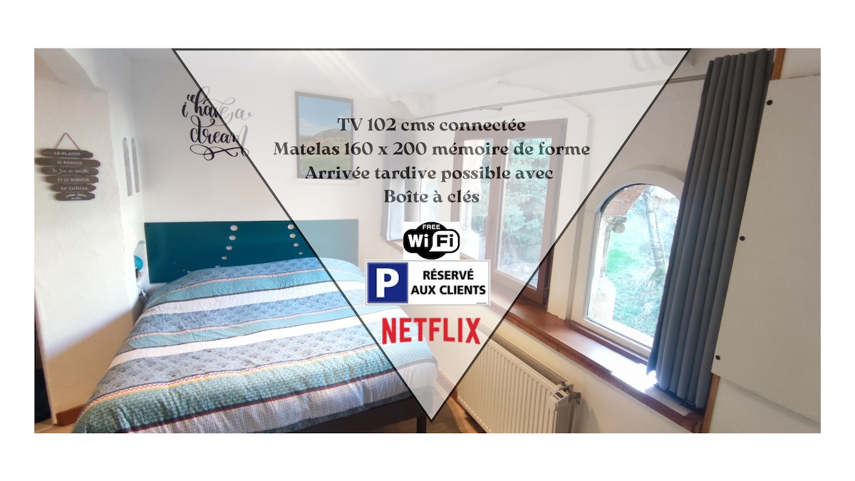 A comfortable sleeping area is featured, showcasing a spacious bed with a memory foam mattress. A 102 cm smart TV is positioned nearby. Natural light enters through a window with blackout curtains, enhancing the inviting ambiance of the space.