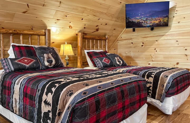 2 eenpersoonsbedden met comfortabele matrassen in de loft. Er is een gemonteerde televisie net boven de bedden.