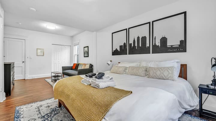 Просторна и спокойна спалня с плюшено легло с размер King, уютна всекидневна и модерно градско изкуство – идеалното място за отдих и възстановяване на енергията след ден в Кливланд.