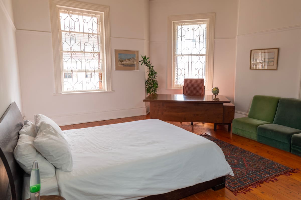 Queen bedroom with sash windows and wooden floors at Utopia co-living in Fresnaye, Cape Town